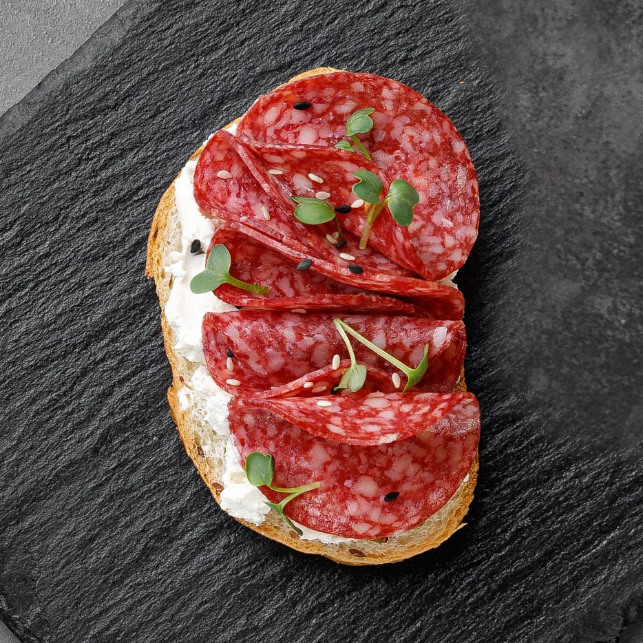 Bruschetta mit Salami, Basilikumpesto, Ruccola und getrockneten Tomaten. 20 Portionen